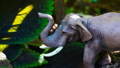 elephant toy, cute elephant miniature on rocks and gravel with ornamental plants background in the...