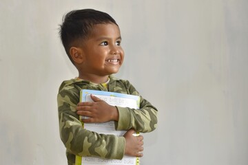 Close up of a smiling boy hugging a book on a white background