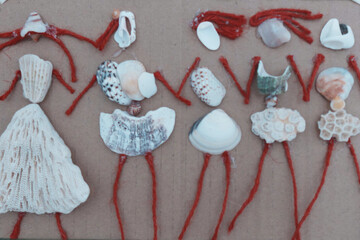 Creative handmade artwork made from seashells, coral pieces, and red yarn, arranged to resemble a group of women holding hands. The image conveys a playful, summery, and artistic vibe, ideal for theme