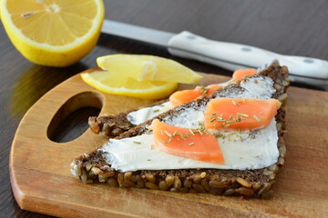 Salmon Sandwich with soft cheese and Lemon on a Wooden Board