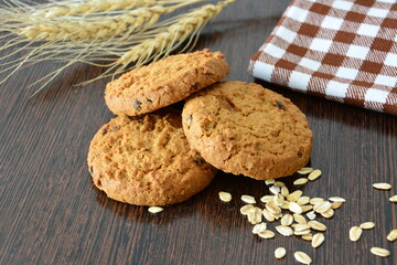 Oatmeal Cookies with chocolate chips on a Wooden Table with ears of wheat and checkered towel