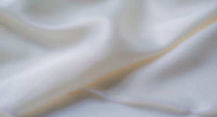 Blurred soft white fabric flows gracefully in gentle waves, enhanced by natural light and creating...