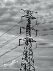 High voltage power lines and pylons captured against dramatic cloudy skies. Suitable for energy,...