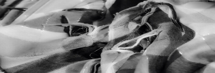 Blurred close-up of black and white fabric strands with soft fraying, focusing on the delicate...