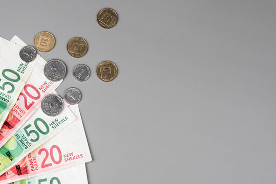 Israel currency 100 and 50 New Israeli shekel (NIS) banknotes alongside agorot coins, on grey background, concept of inflation, economic crisis, rising prices, and financial management.