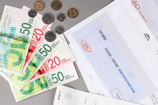 Israel currency New Israeli shekel (NIS) banknotes and agorot coins, with bills for electricity, water, and taxes, concept of inflation, economic crisis, rising prices, and financial management.