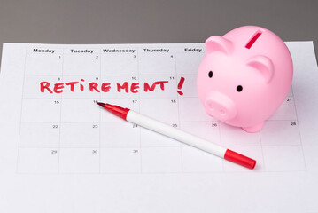 Piggy bank and calendar with the word 'Retirement' written on it, as savings for retirement and planning. Concept of early retirement, the Financial Independence, Retire Early movement (FIRE).