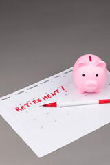 Piggy bank and calendar with the word 'Retirement' written on it, as savings for retirement and planning. Concept of early retirement, the Financial Independence, Retire Early movement (FIRE).