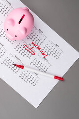 Piggy bank on calendar with the words 'Vacation' written on it, symbolizing saving money for travel, financial planning, and budgeting for a dream getaway. Concept of vacation savings and planning.