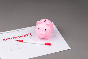 Piggy bank and calendar with the word 'Retirement' written on it, as savings for retirement and planning. Concept of early retirement, the Financial Independence, Retire Early movement (FIRE).