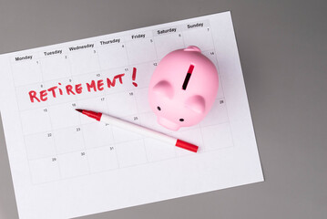 Piggy bank and calendar with the word 'Retirement' written on it, as savings for retirement and planning. Concept of early retirement, the Financial Independence, Retire Early movement (FIRE).