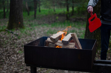 Lighting firewood in the grill. A burner in hand, flames.