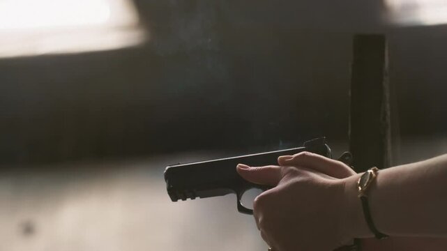 Woman shoots a pistol at a shooting range, sports shooting. Female makes a gun shot in an army shooting gallery. Real weapon in police. Lady is aiming at the target. Life protection and bodyguard