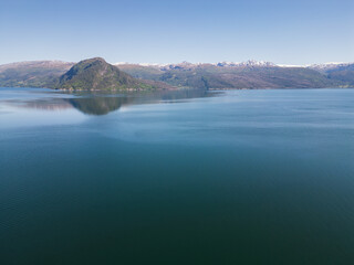 Nature of Norway, photo drone view: serene Hardangerfjord, blue waters and mountain ranges under a clear sky.