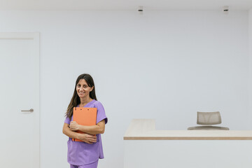 Optometrist woman holding a clipboard smiling at the camera in her office