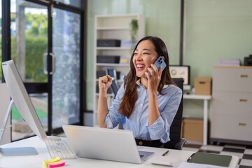Overjoyed charming excited woman business woman worker using smartphone and laptop working in...