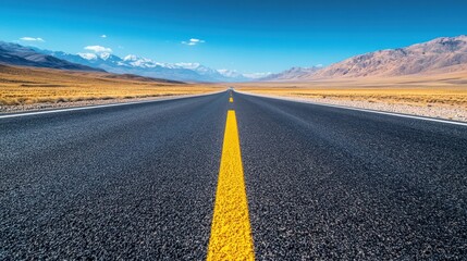 Empty asphalt road stretching into the distance, leading to snow-capped mountains under a clear sky.  Vast, 