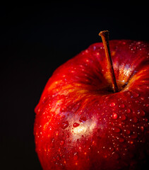 Red apple with water droplets on a black background