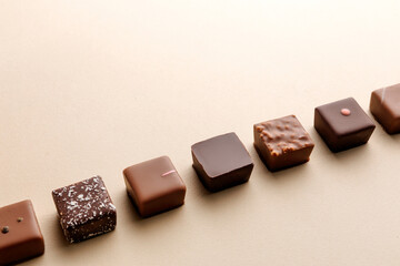 Minimal overhead shot of chocolate squares on beige background, elegant candy dessert composition