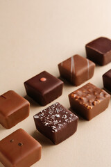 Minimal overhead shot of chocolate squares on beige background, elegant candy dessert composition