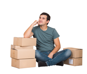 Pensive young man seated on the floor and leaning on cardboard boxes keeps hand under cheek and dreams. Ready for moving to a new house, transparent background