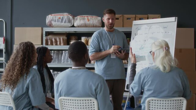 Stab shot of intercultural team of volunteers having discussion of workplan at food donation center