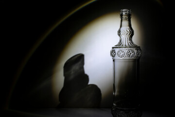 botella de vidrio transparente con adornos o filigranas con foco directo y sombras detrás para...