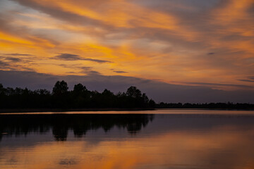 Reflective surface beautiful orange and pink sky background reflective look in large lake in Latvia near city Saldus, water sunset reflection on water surface