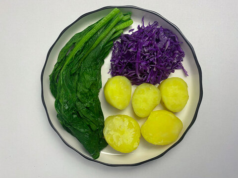 Boiled caisim, red cabagge, and potato on plate. Isolated on white background.