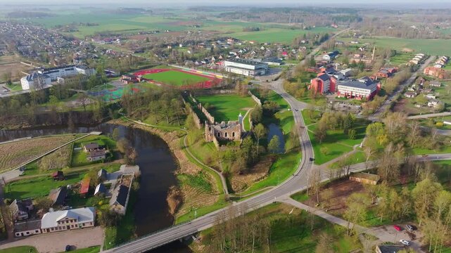 Historic Dobele Castle ruins nestled by the river and town in vivid green spring