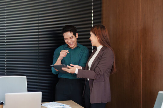 Digital Collaboration and Engagement. Colleagues reviewing a presentation on a tablet, smiling and exchanging ideas.