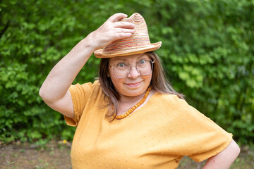 Confident Happy mature woman in yellow outfit, smiling gently, with hat, in mustard clothing...