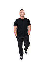 A handsome dark-haired man in a black T-shirt, trousers and sneakers on a white background