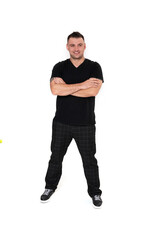 A handsome dark-haired man in a black T-shirt, trousers and sneakers on a white background