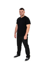 A handsome dark-haired man in a black T-shirt, trousers and sneakers on a white background