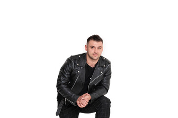 A handsome dark-haired man in a black leather jacket, black T-shirt, trousers and sneakers on a white background
