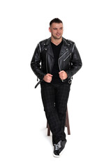 A handsome dark-haired man in a black leather jacket, black T-shirt, trousers and sneakers on a white background
