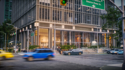 Establishing Exterior Shot of Busy City Intersection. Modern Glass Building With Shops and Caf&eacute;. Vehicles Move Through, Pedestrians Cross, and Traffic Lights Manage the Flow. Wide Shot