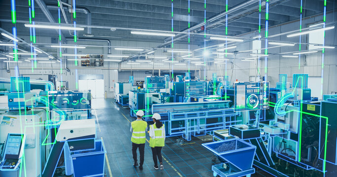 Two Engineers in Safety Gear Use a Tablet to Interact With Holographic Data in a High-tech Factory, Surrounded by Advanced Machinery and Digital Interfaces, Illustrating a Futuristic Manufacturing