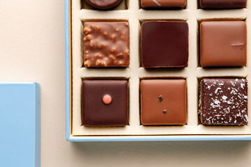 Minimal flatlay of open box with chocolate squares on beige background, elegant candy dessert packaging mockup concept