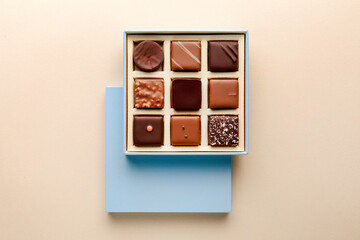 Minimal flatlay of open box with chocolate squares on beige background, elegant candy dessert packaging mockup concept