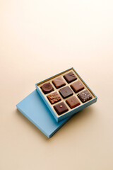 Minimal flatlay of open box with chocolate squares on beige background, elegant candy dessert packaging mockup concept