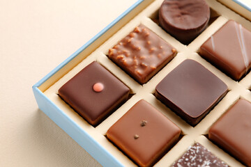 Minimal flatlay of open box with chocolate squares on beige background, elegant candy dessert packaging mockup concept