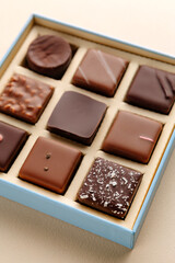 Minimal flatlay of open box with chocolate squares on beige background, elegant candy dessert packaging mockup concept
