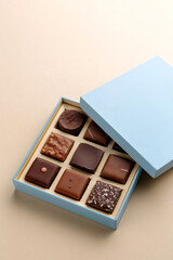 Minimal flatlay of open box with chocolate squares on beige background, elegant candy dessert packaging mockup concept