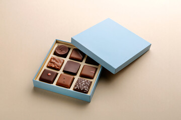 Minimal flatlay of open box with chocolate squares on beige background, elegant candy dessert packaging mockup concept
