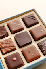 Minimal flatlay of open box with chocolate squares on beige background, elegant candy dessert packaging mockup concept