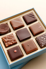 Minimal flatlay of open box with chocolate squares on beige background, elegant candy dessert packaging mockup concept