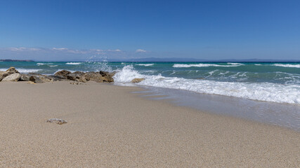 Wellen am Sandstrand mit Felsen unter blauem Himmel – Griechen