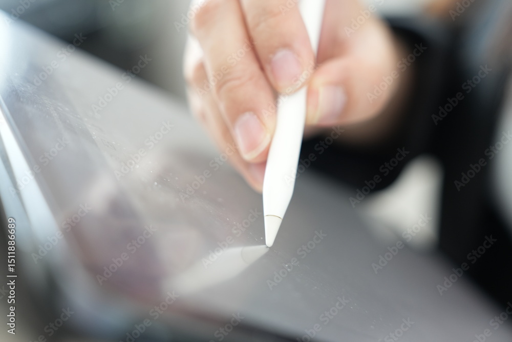 Poster a hand using a digital stylus to write or draw on a tablet screen.